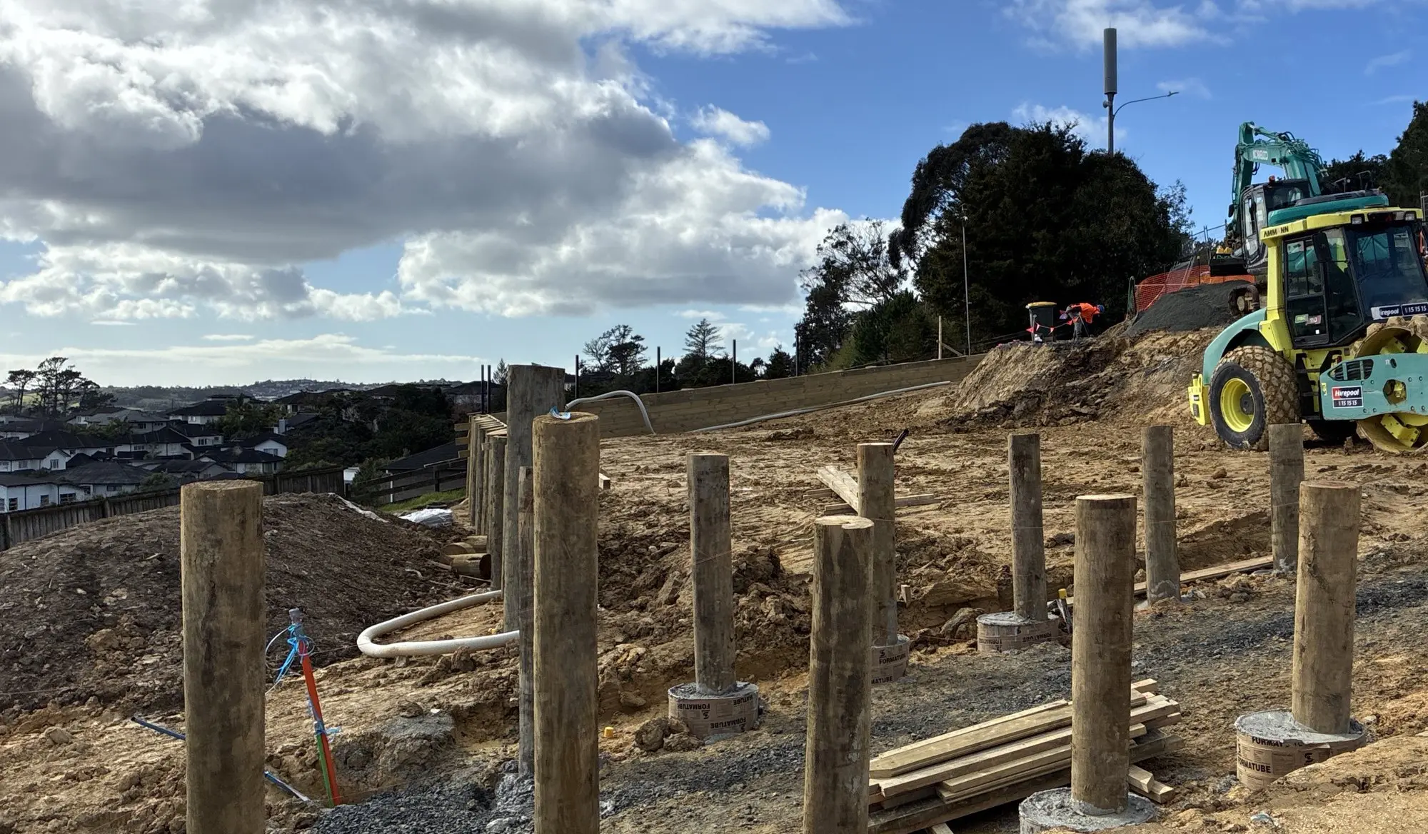 Timber pole retaining wall posts with earthworks underway on the lots behind