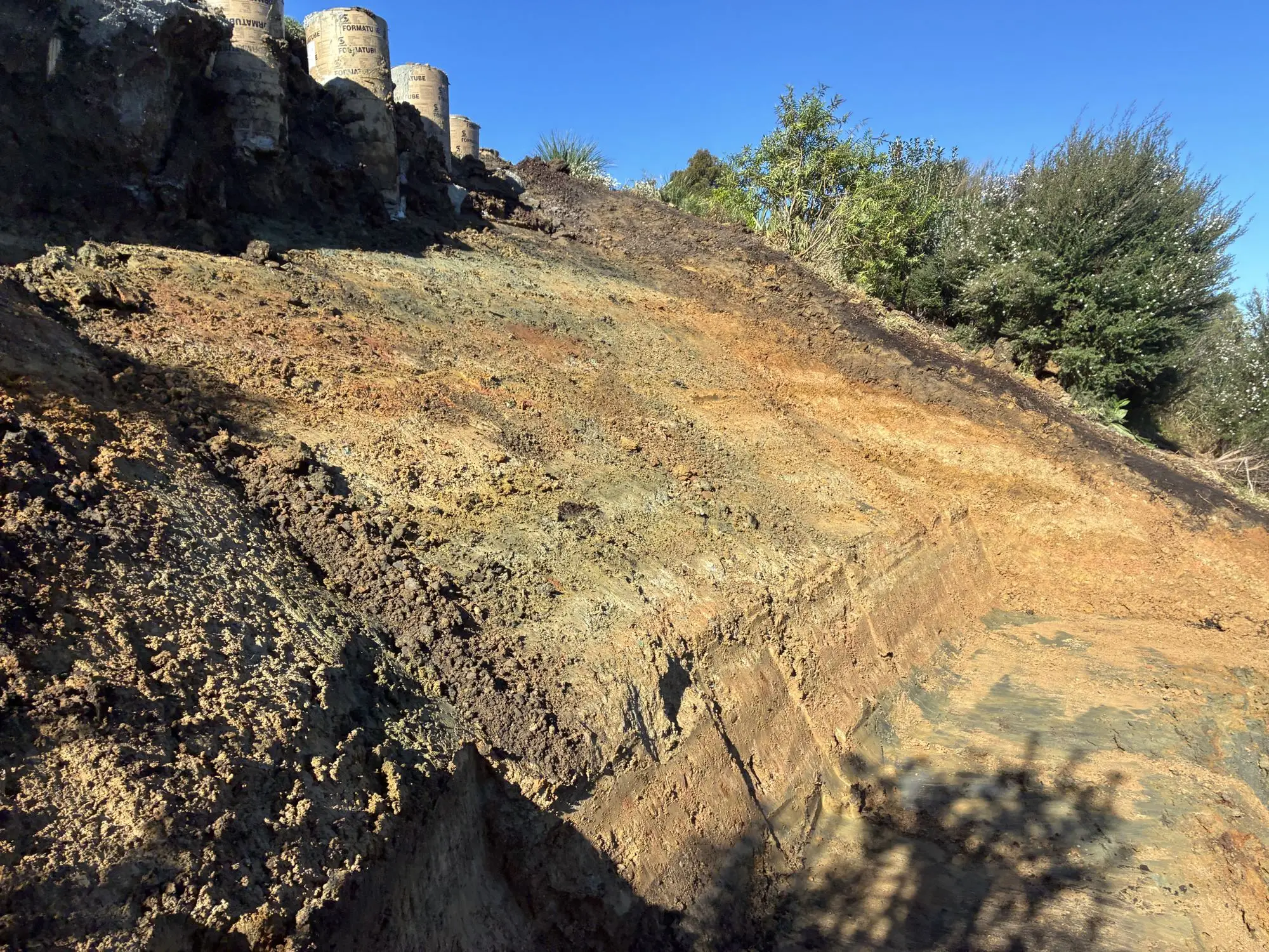 Slope excavation exposing weathered soils below a house