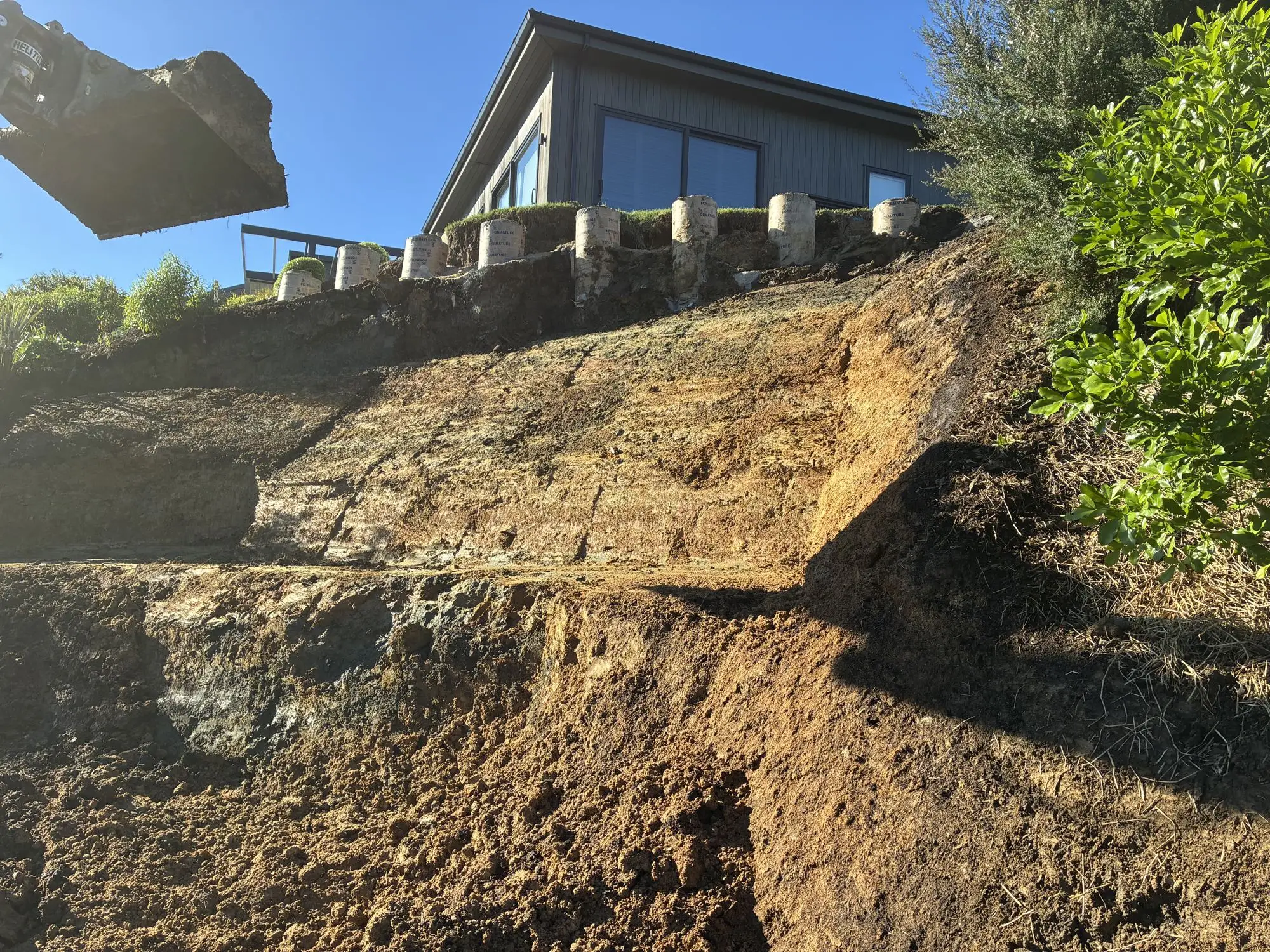 Excavation removing slipped material below a house in Matakana
