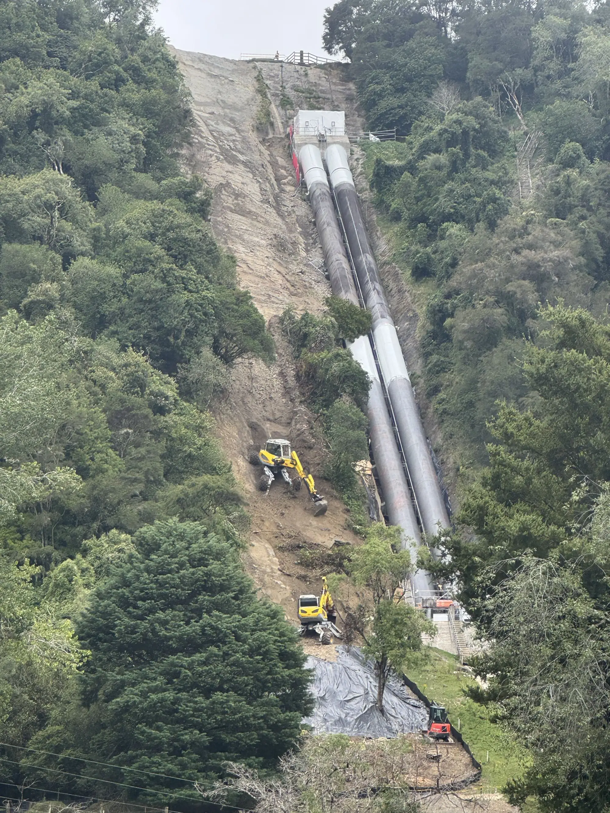 Penstock pipelines running down a steep slope with remediation works underway